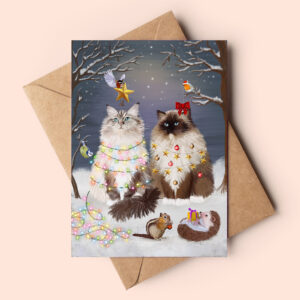 Ragdoll cat christmas card featuring two fluffy ragdoll cats in a snowy forest being dressed up as christmas trees by the cute forest animals.