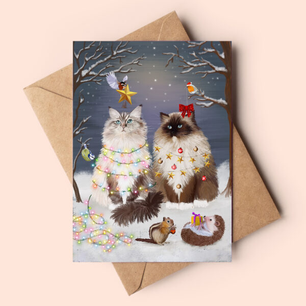 Ragdoll cat christmas card featuring two fluffy ragdoll cats in a snowy forest being dressed up as christmas trees by the cute forest animals.