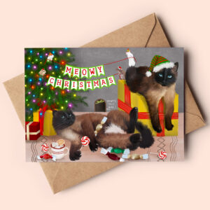 Siamese Cat Christmas card. Two siamese lounging by the christmas tree. One is lying lazily under it with candies scattered all around him, the other hanging off a large Christmas gift. Little mice holding Meowy Christmas banner in the background.