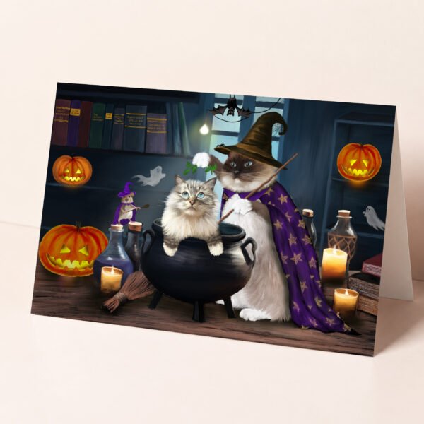 Ragdoll cat halloween card featuring one fluffy kitty in a cauldron and another one wearing a witch's hat and a starry robe.